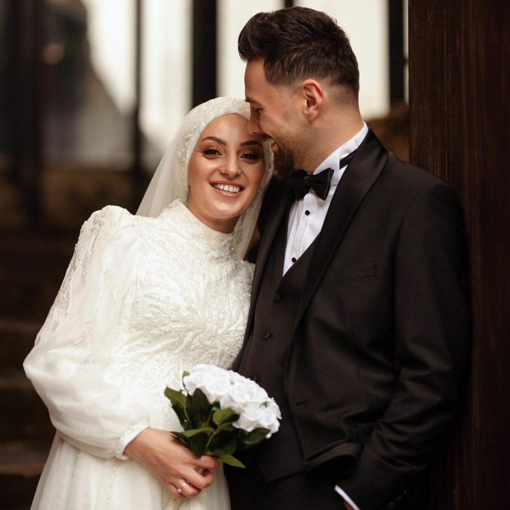 Happy bride and groom in wedding attire sharing a joyful moment indoors.